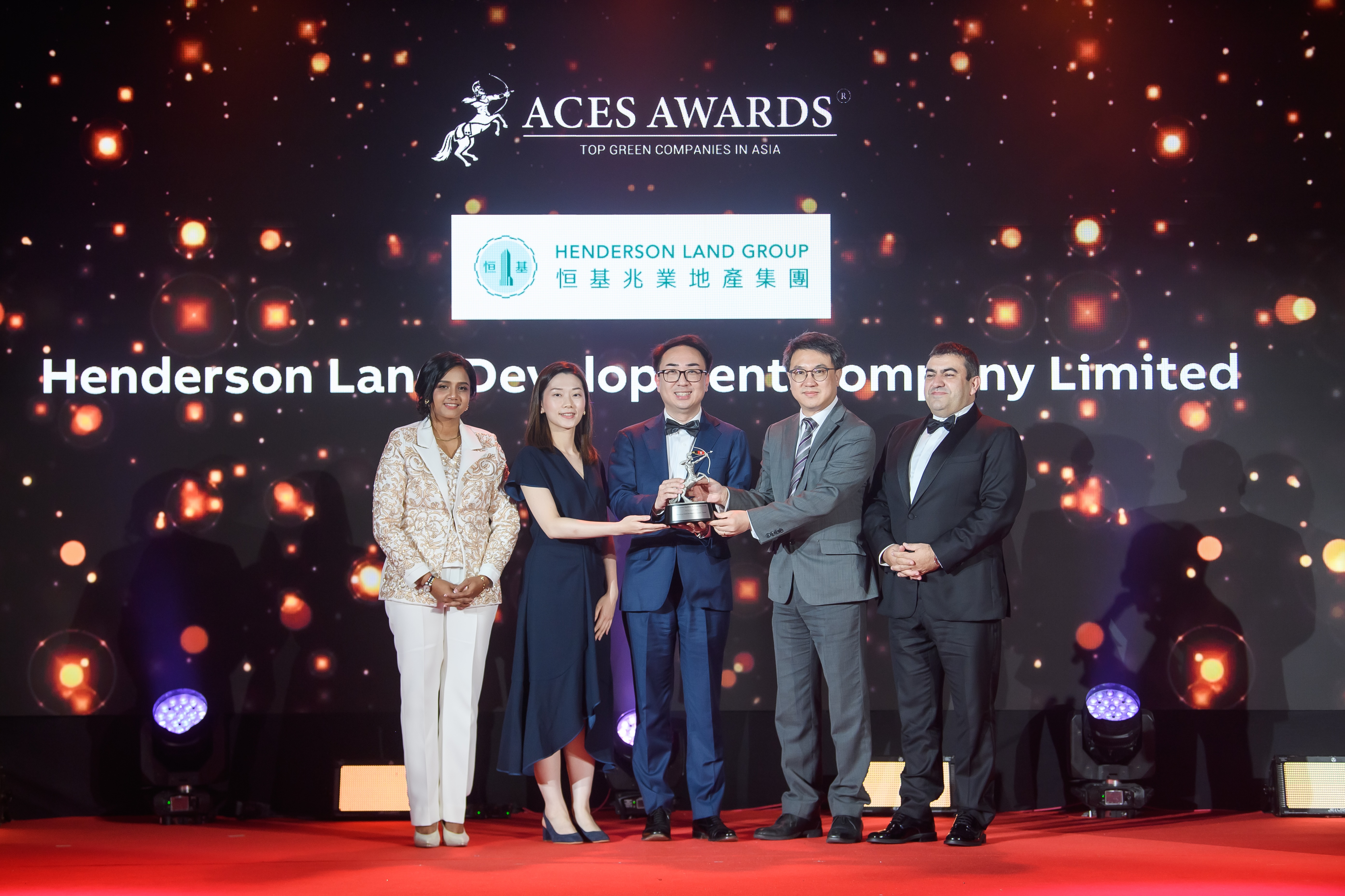 Johnny Yu, Head of Sustainability and Advisor to the Chairman, Henderson Land Development Company Limited (Centre), proudly accepts the ACES Awards 2024 Top Green Companies in Asia accolade on stage. Standing alongside him are Edward Chan, Deputy General Manager (Right Centre), and Hazel Cheng, Project Manager - Sustainability (Left Centre), representing the company’s unwavering commitment to sustainability. The award is presented by Dr Shanggari Balakrishnan, President of the ACES Awards (Far Left), and Luis Bueno Nieto, Advisor to the ACES Council (Far Right), marking a moment of triumph and recognition for Henderson Land Development’s leadership in driving green innovation across Asia.